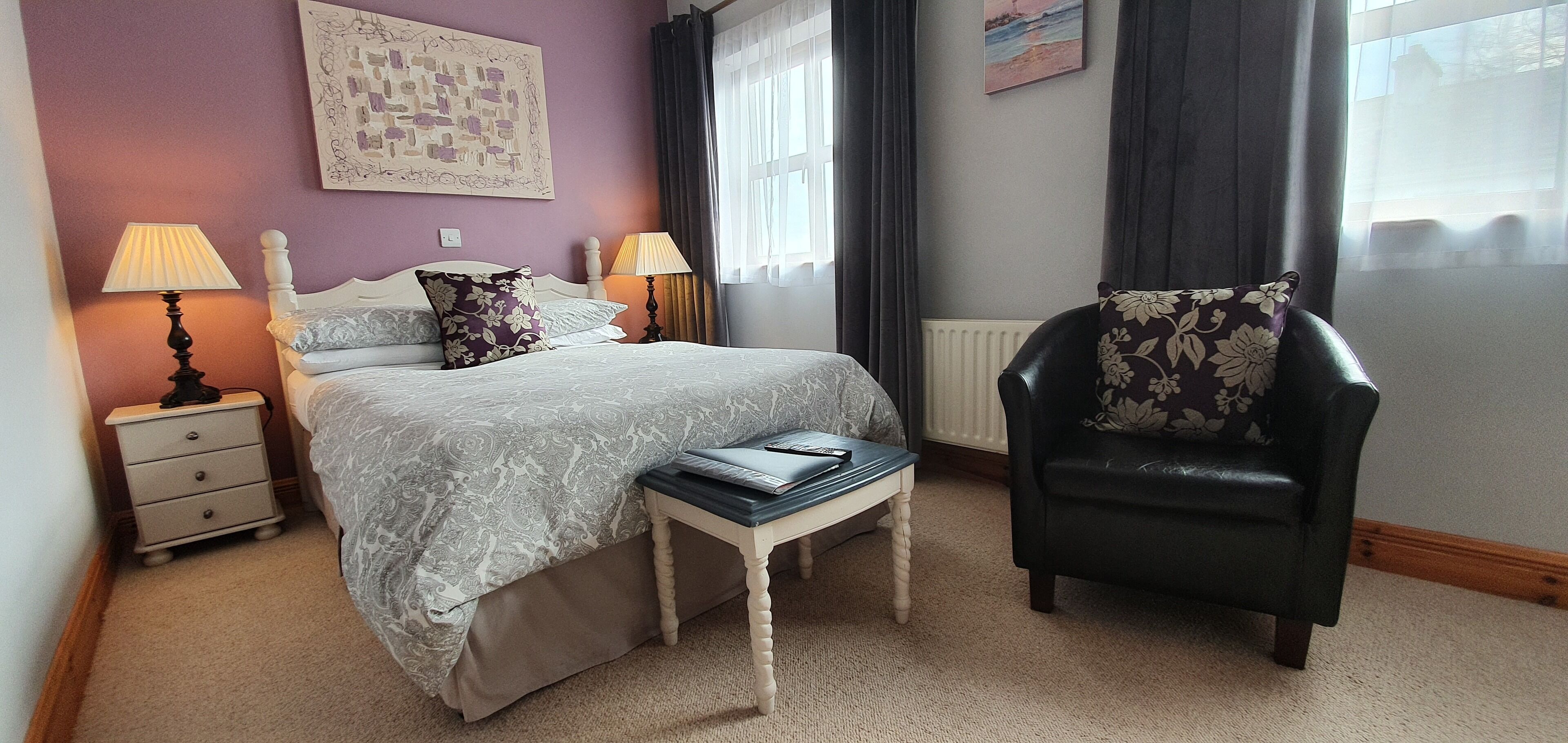 A bedroom with a bed, bedside tables, a chair, and a window with curtains.