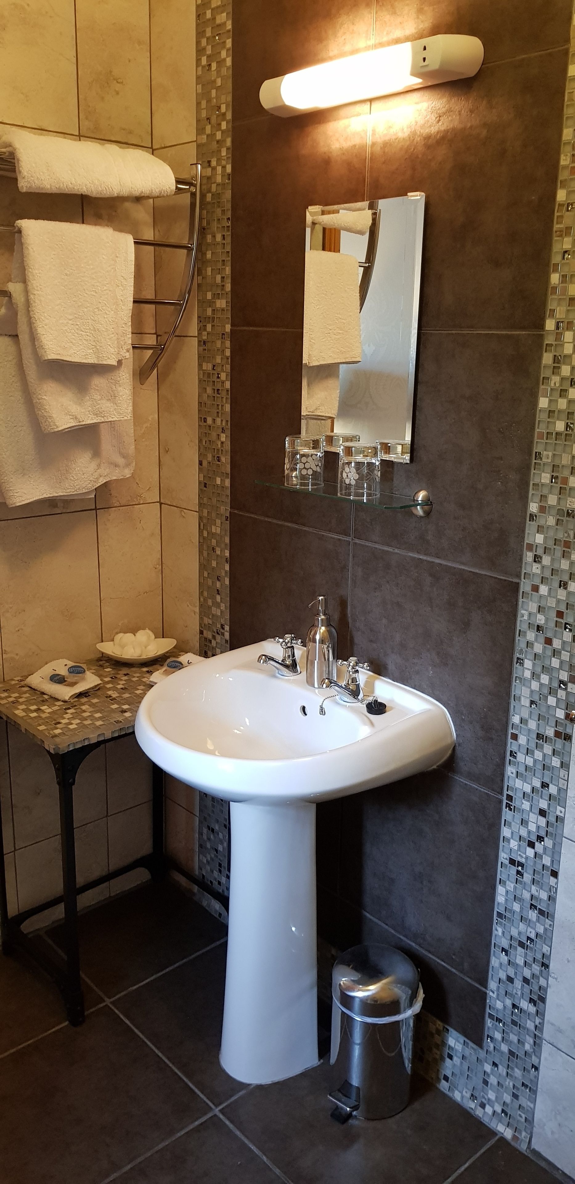 Un baño con un lavabo blanco, un espejo y un perchero para toallas.