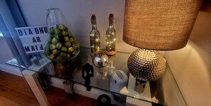 A glass table with decorative items including a jar of apples, two bottles, a lamp, and a sign with text. - Church View B&B (Gurteen)