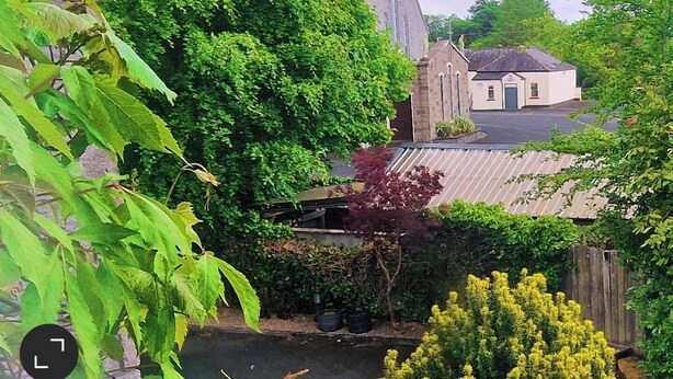 A church with a tall steeple and a small adjacent building. - Church View B&B (Gurteen)