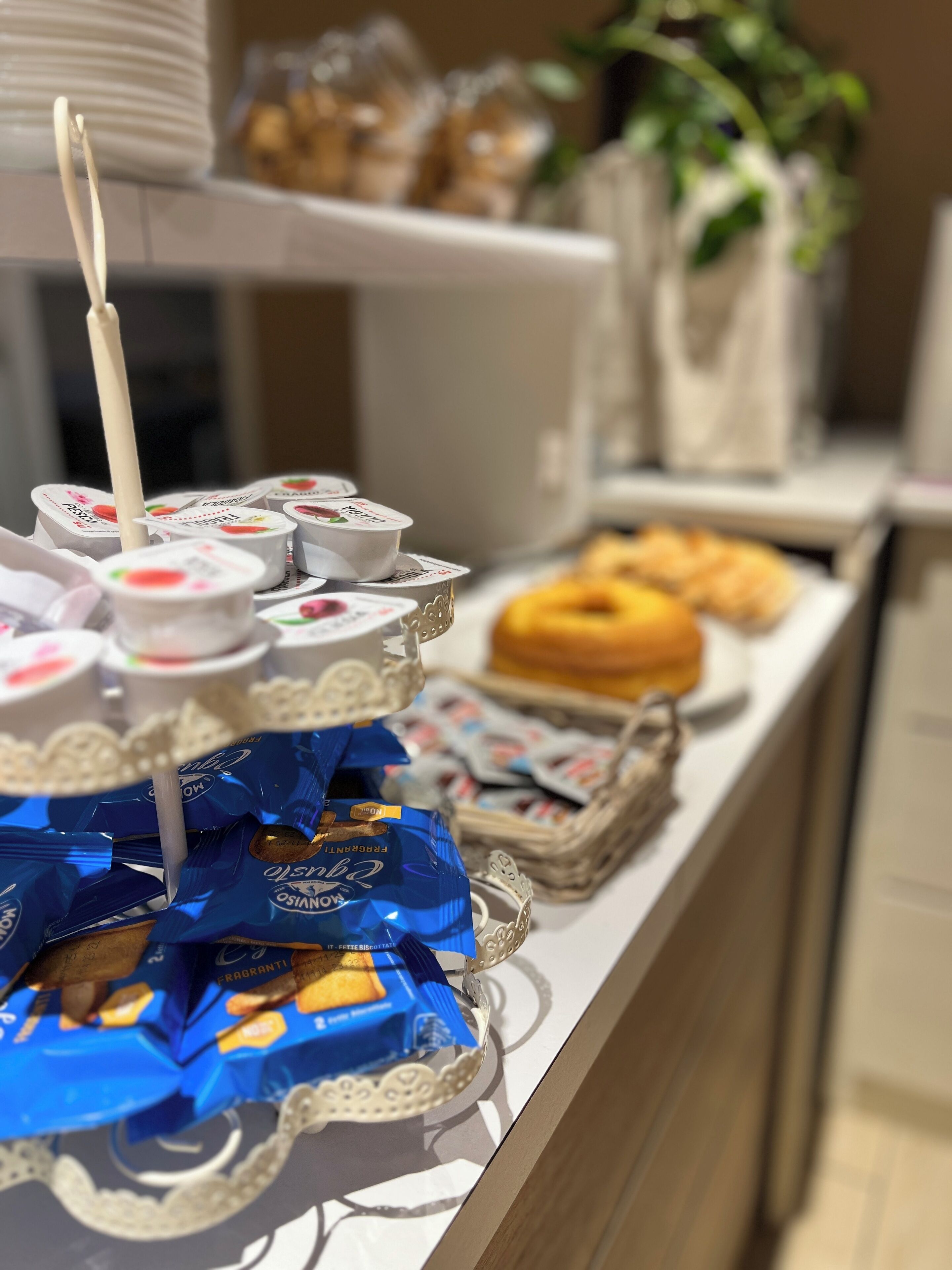 Una mesa de bufé con diversos alimentos, como vasos de yogur, pasteles y bocadillos envasados.