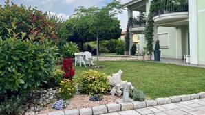 A well-maintained garden with various plants and a stone pathway leading to a building with a balcony. - Eremes Rooms & Apartments (Cuneo)