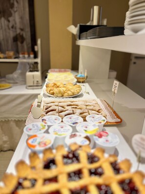 A buffet table with various food items including pastries, desserts, and yogurt.