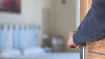A person opening a wooden door with a metallic handle.