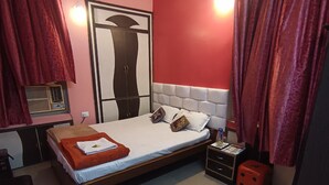 Un dormitorio con cama, mesita de noche, silla, armario y ventilador de techo.