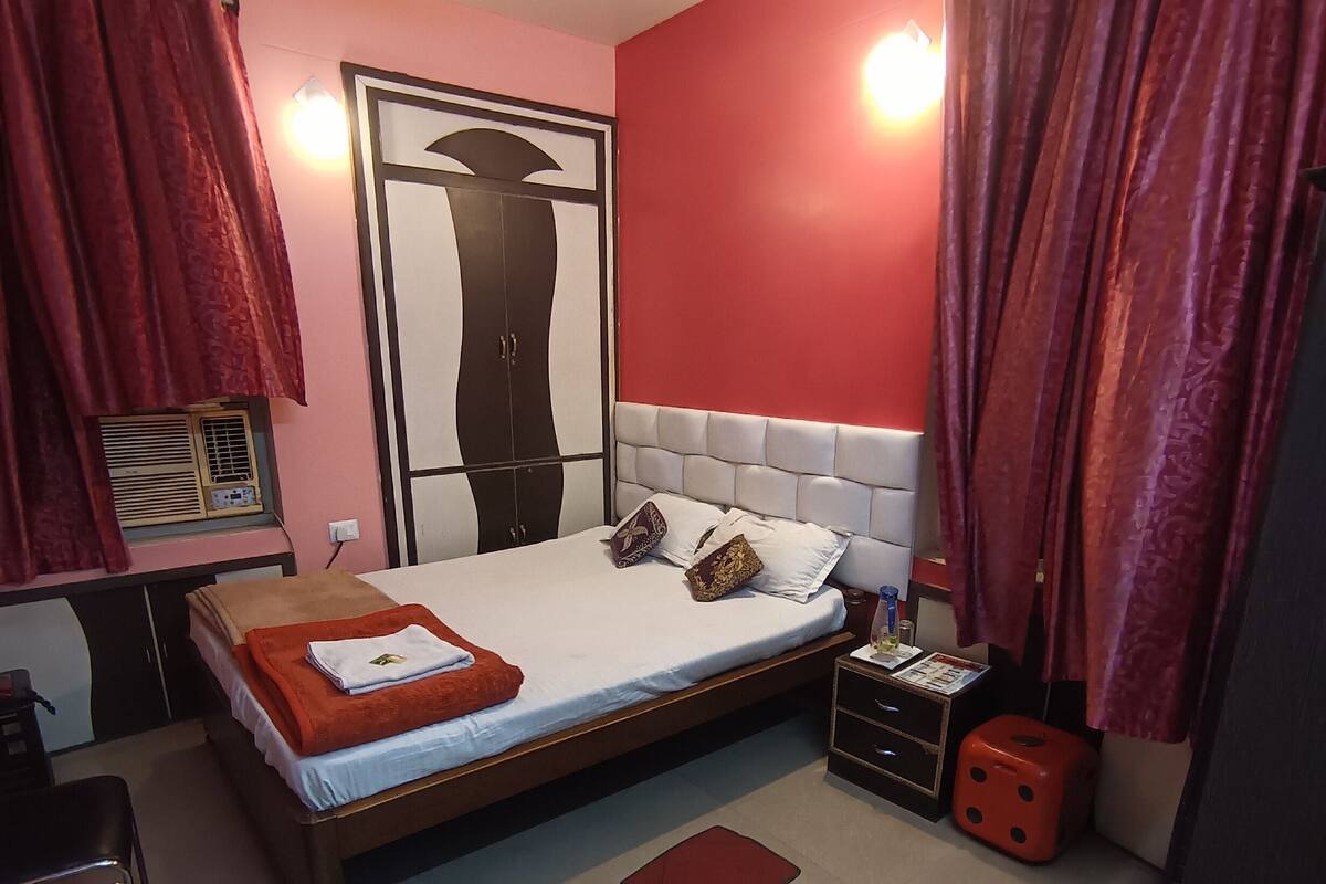 Ein Schlafzimmer mit Bett, Nachttisch, Stuhl, Kleiderschrank und Deckenventilator.