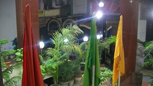 Un vestíbulo con plantas en macetas, una cortina roja y una bandera verde y amarilla.