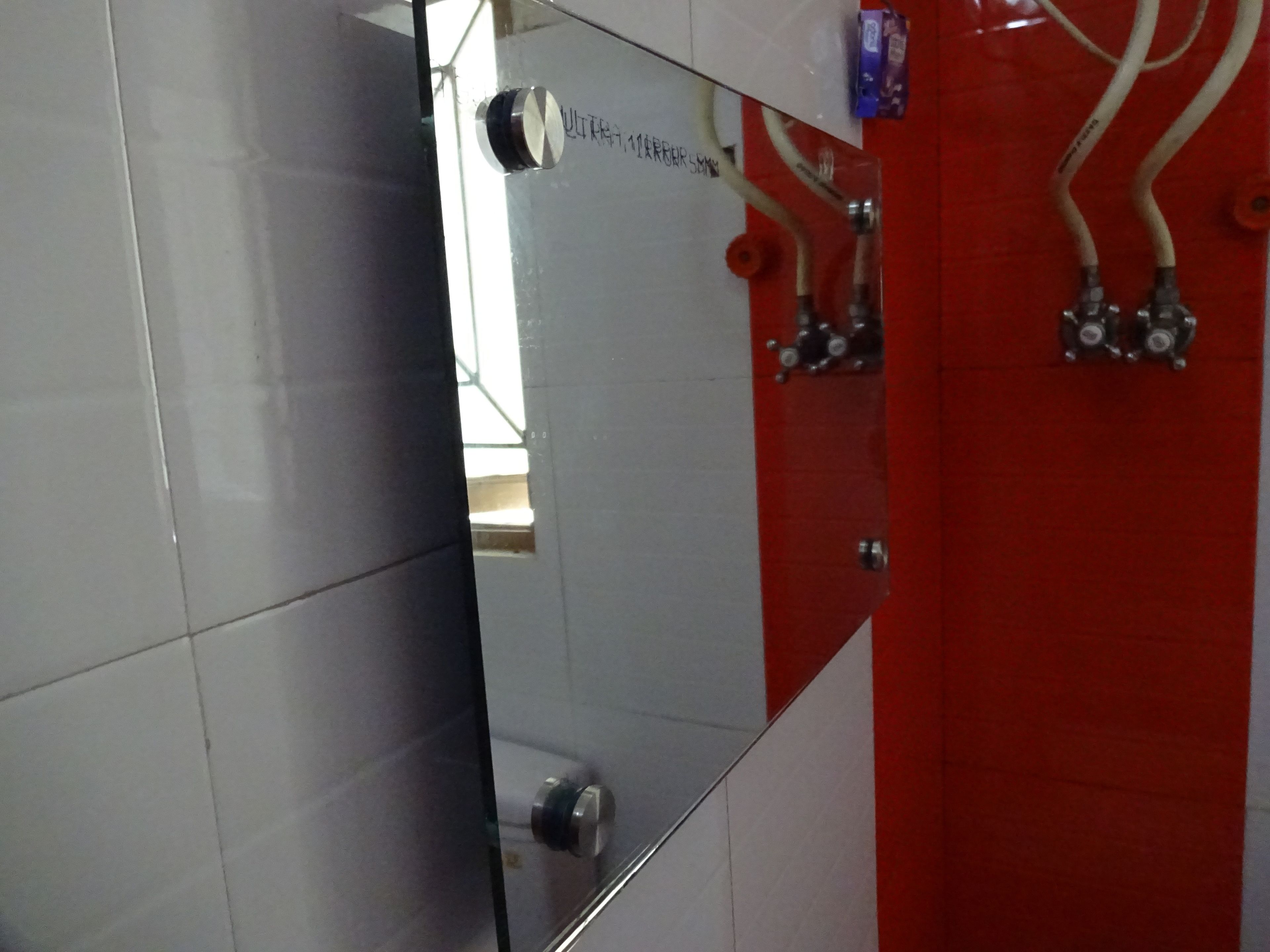 A bathroom with a mirror, a red wall, and a white tiled floor.