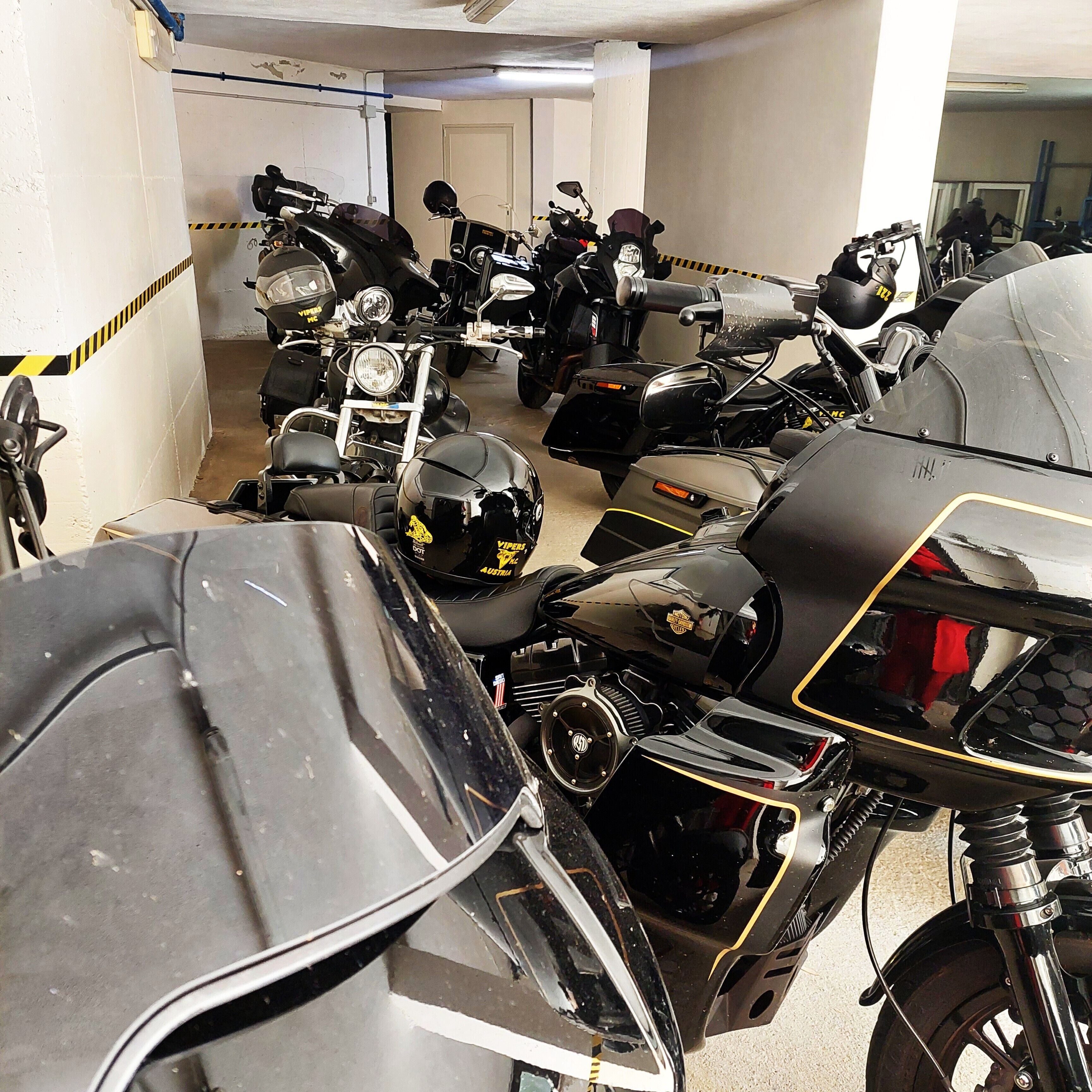 A parking garage with multiple motorcycles parked in rows.