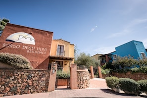 A building with a stone wall entrance and a sign reading "BORGO DEGLI ULVI RESIDENCE." - Borgo degli Ulivi Residence (Tortoli)