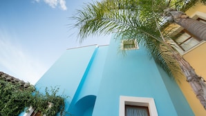 Ein Gebäude mit blauer Fassade, einer Palme und einem Fenster.