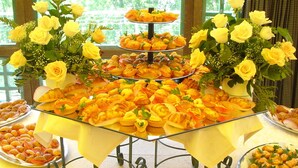 Una mesa de bufé con varios niveles de comida, decorada con rosas amarillas.