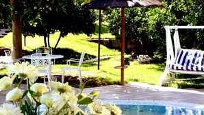 Un área junto a la piscina con una silla de descanso blanca, una mesa y sillas.