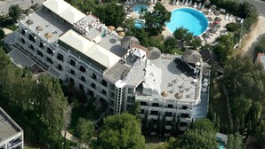 Un hotel con piscina en la azotea, varios pisos y vegetación circundante.