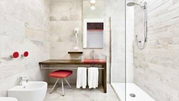 Un bagno moderno con parete in marmo, mobile lavabo in legno, uno sgabello rosso, lavandino bianco e box doccia in vetro.