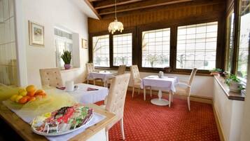 A cozy dining area with wooden beams, large windows, and a red carpet.