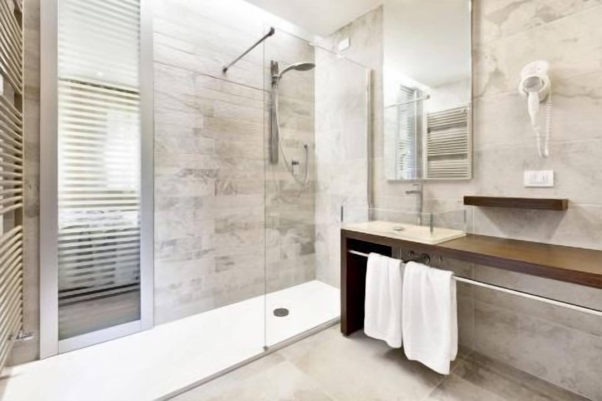 Un baño moderno con ducha de vidrio, tocador con espejo y barra para toallas.