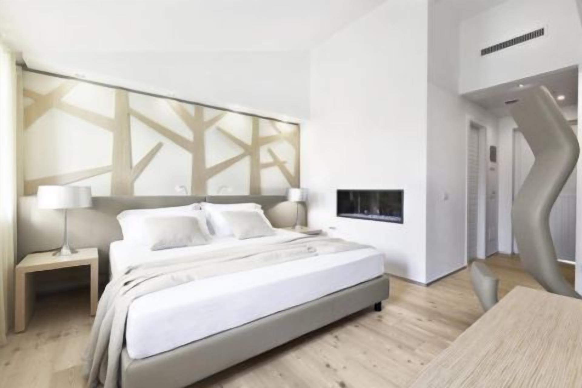 Ein modernes Hotelzimmer mit einem großen Bett, Nachttischen und einem außergewöhnlichen Wanddesign.