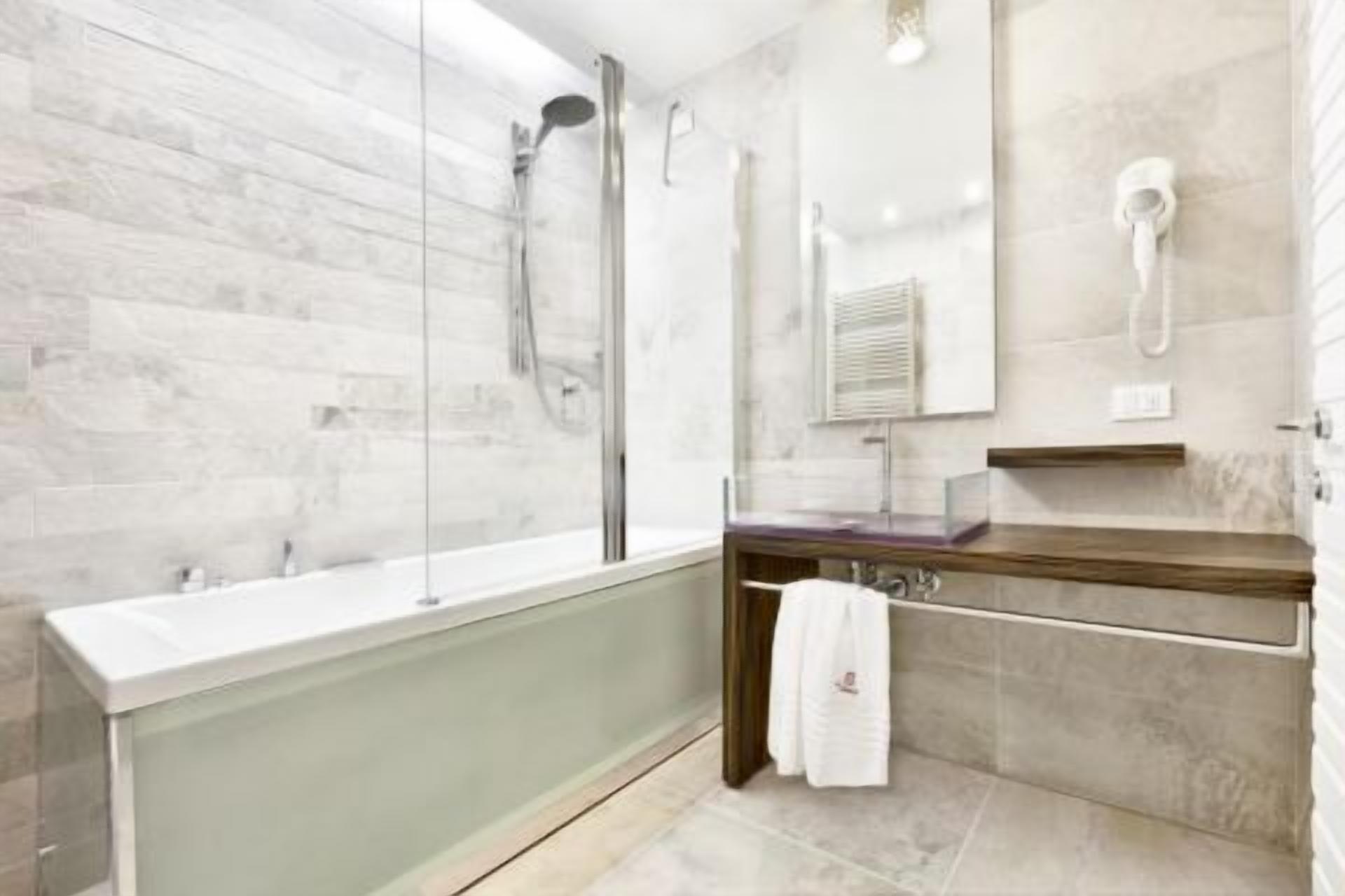 A modern bathroom with a glass-enclosed bathtub, a wooden vanity, and a large mirror.