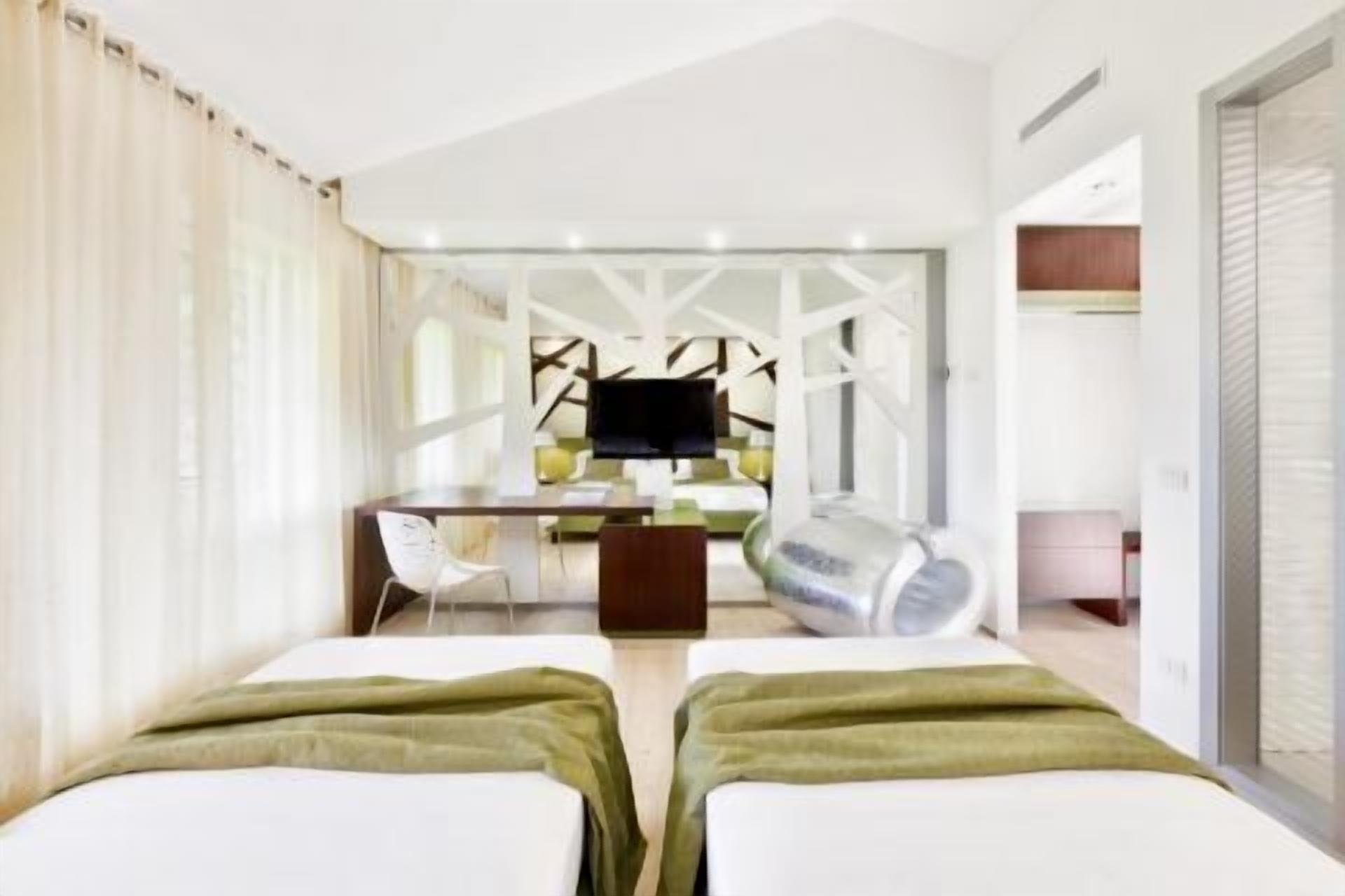 Una habitación de hotel con dos camas, un escritorio, una silla y un televisor.