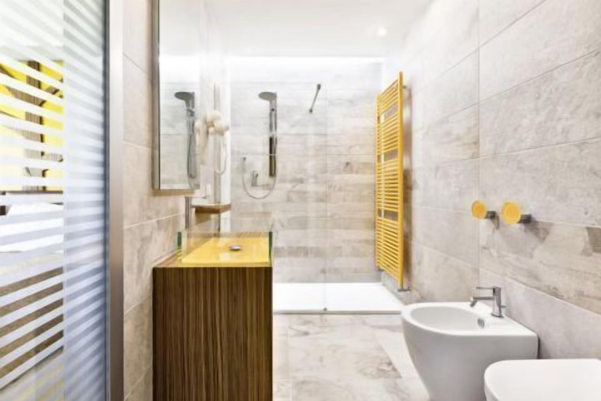 Un baño moderno con tocador de madera, una bañera independiente y un lavabo sobre pedestal.