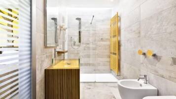 Un baño moderno con tocador de madera, una bañera independiente y un lavabo sobre pedestal.