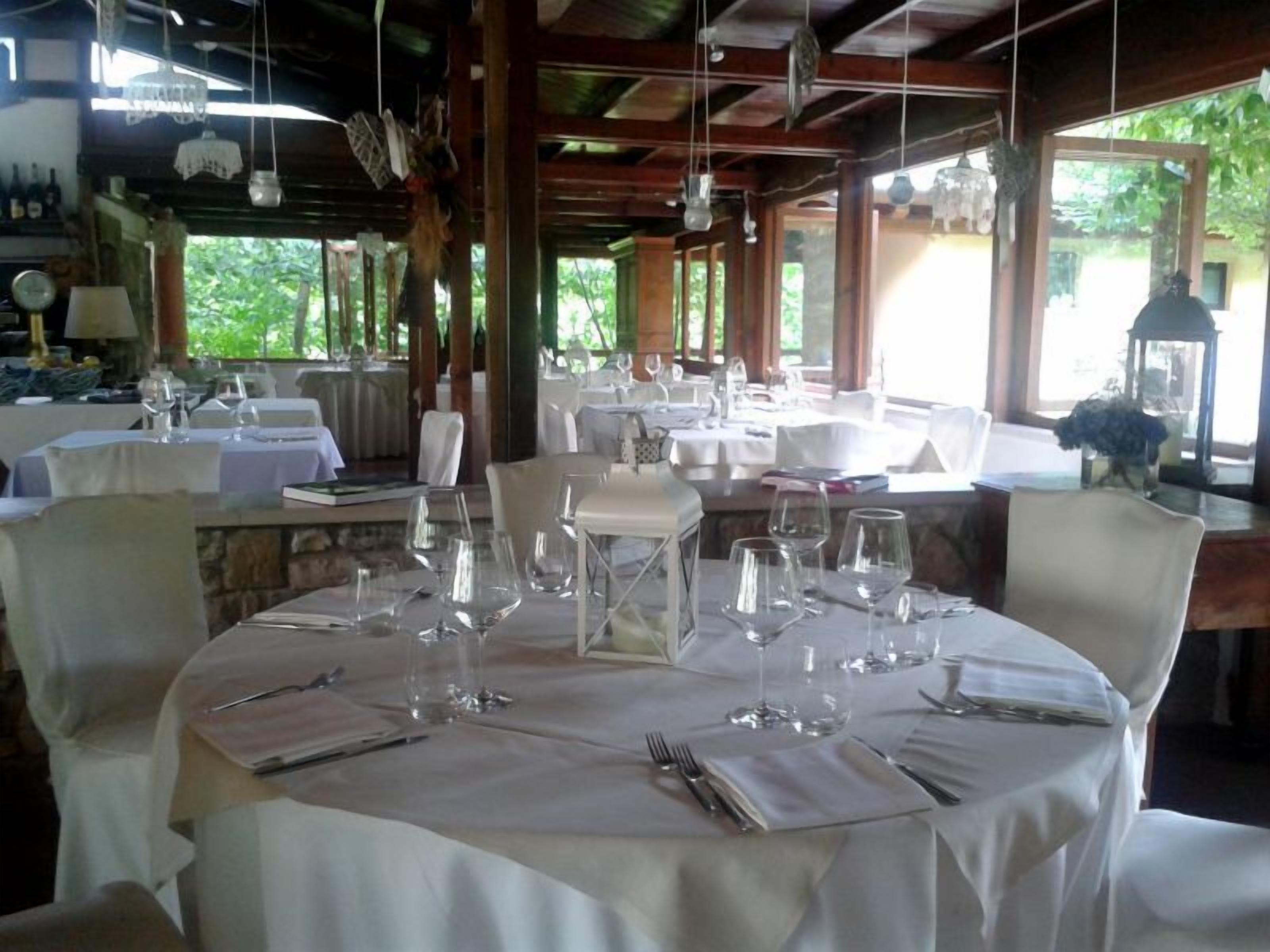 Un restaurant avec des tables rondes dressées pour le repas, agrémentées de nappes blanches et de chaises.