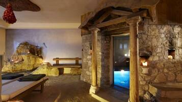 Cozy space with a stone fireplace, wooden beams, and a bench.