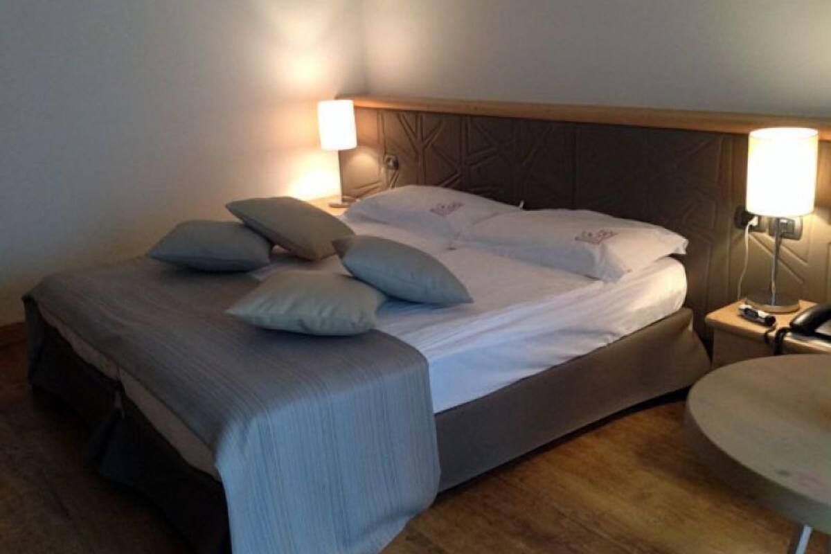 A neatly made bed with pillows and a bedside table with a lamp.