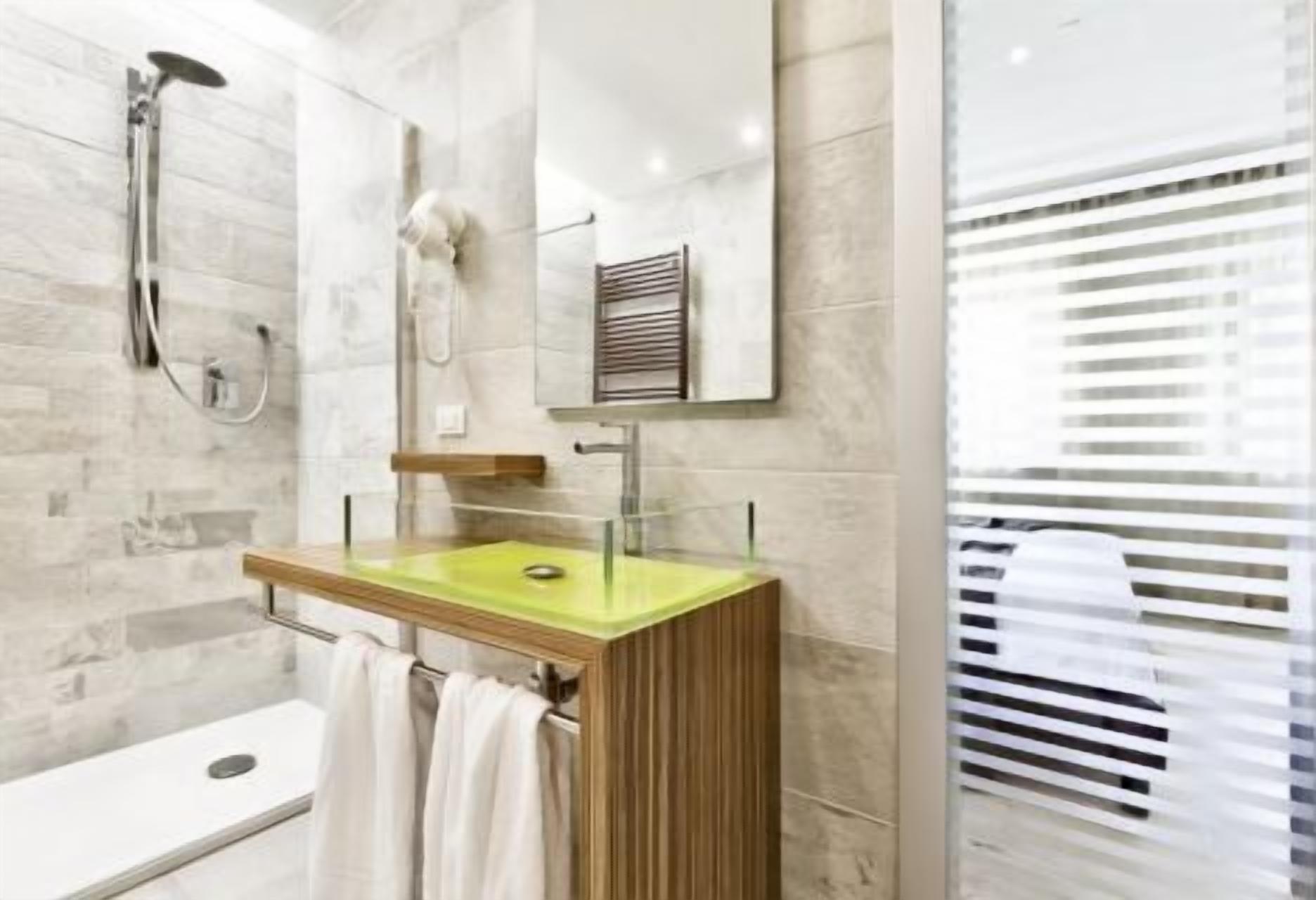 Ein modernes Badezimmer mit einer gläsernen Dusche, einem Holzlagerflansch mit einem grünen Waschbecken und einem großen Spiegel.