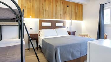 Un dormitorio con literas, una cama individual, paneles de madera en la pared, una mesita de noche y un escritorio pequeño.
