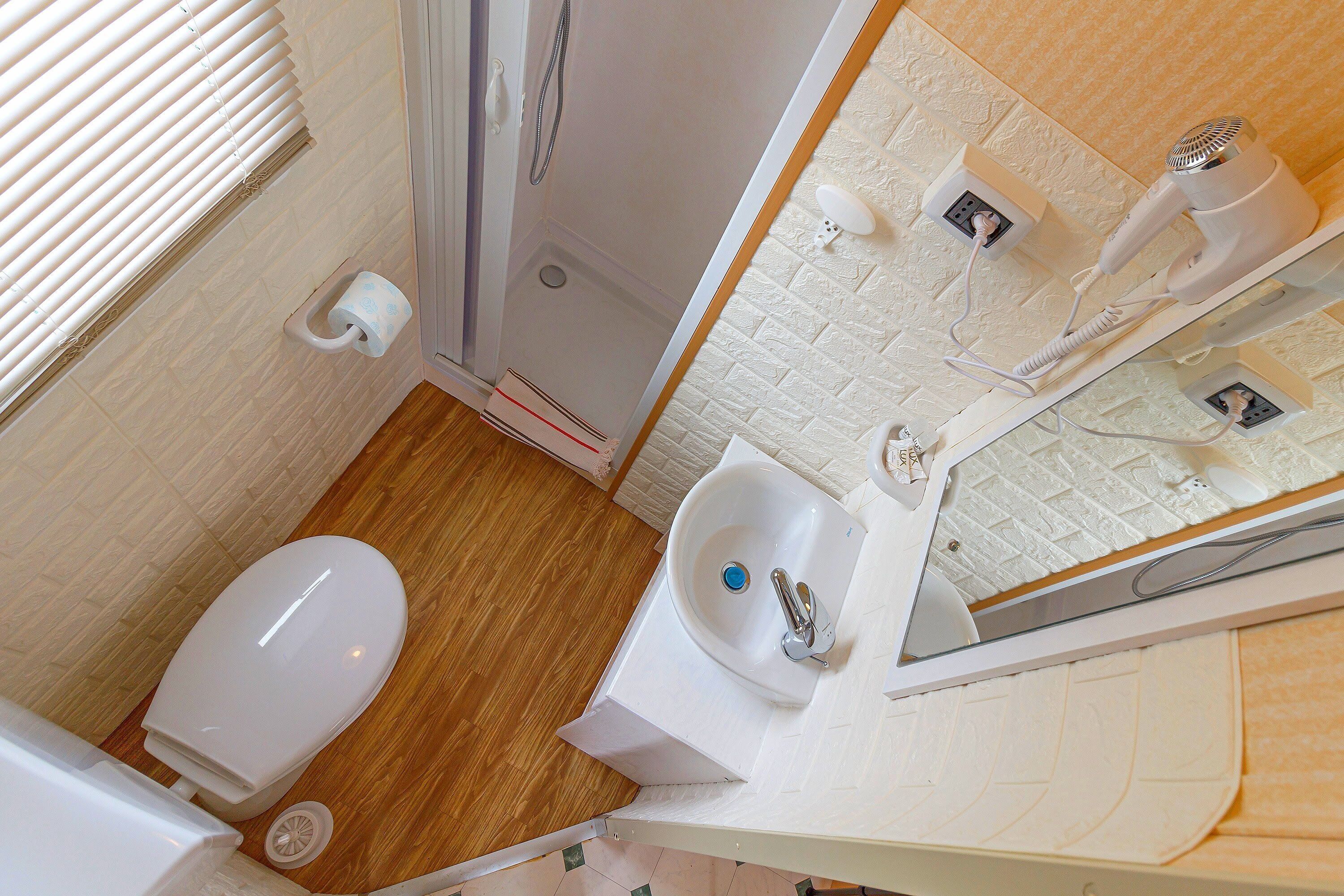 Une petite salle de bain comprenant des toilettes, un lavabo et une douche.