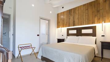 A bedroom with a bed, bedside tables, a wooden headboard, and a small bench by the door.
