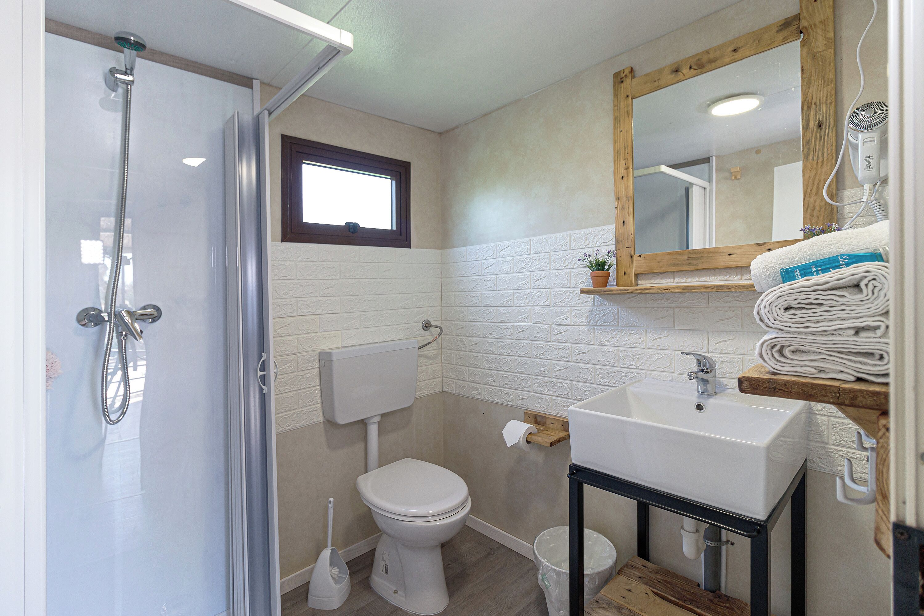 Une salle de bain équipée d’une douche, de toilettes, d’un lavabo et d’un miroir.