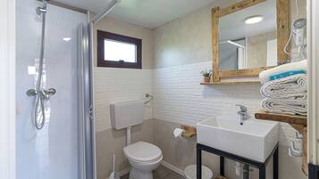 Une salle de bain équipée d’une douche, de toilettes, d’un lavabo et d’un miroir.