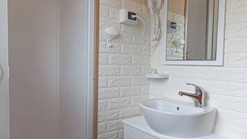 Un bagno con un lavandino bianco, uno specchio e una doccia.