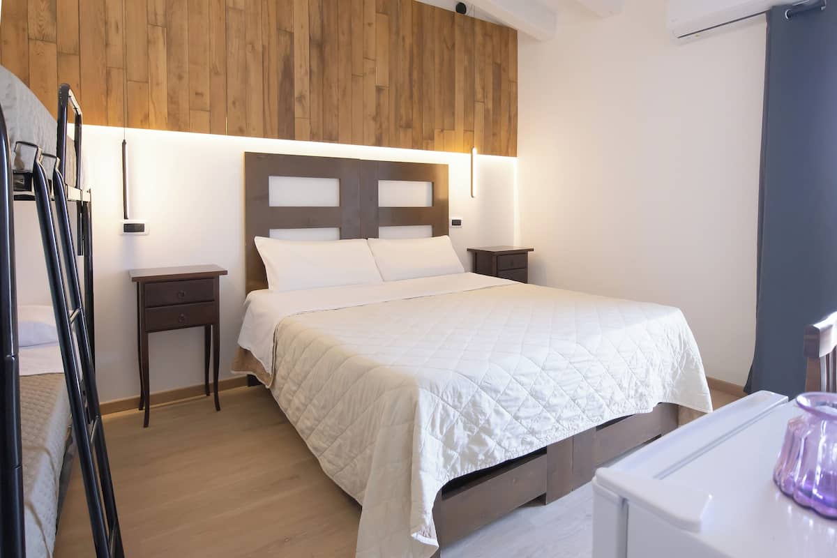 A neatly arranged bedroom with a bed, bedside tables, and a wooden headboard.