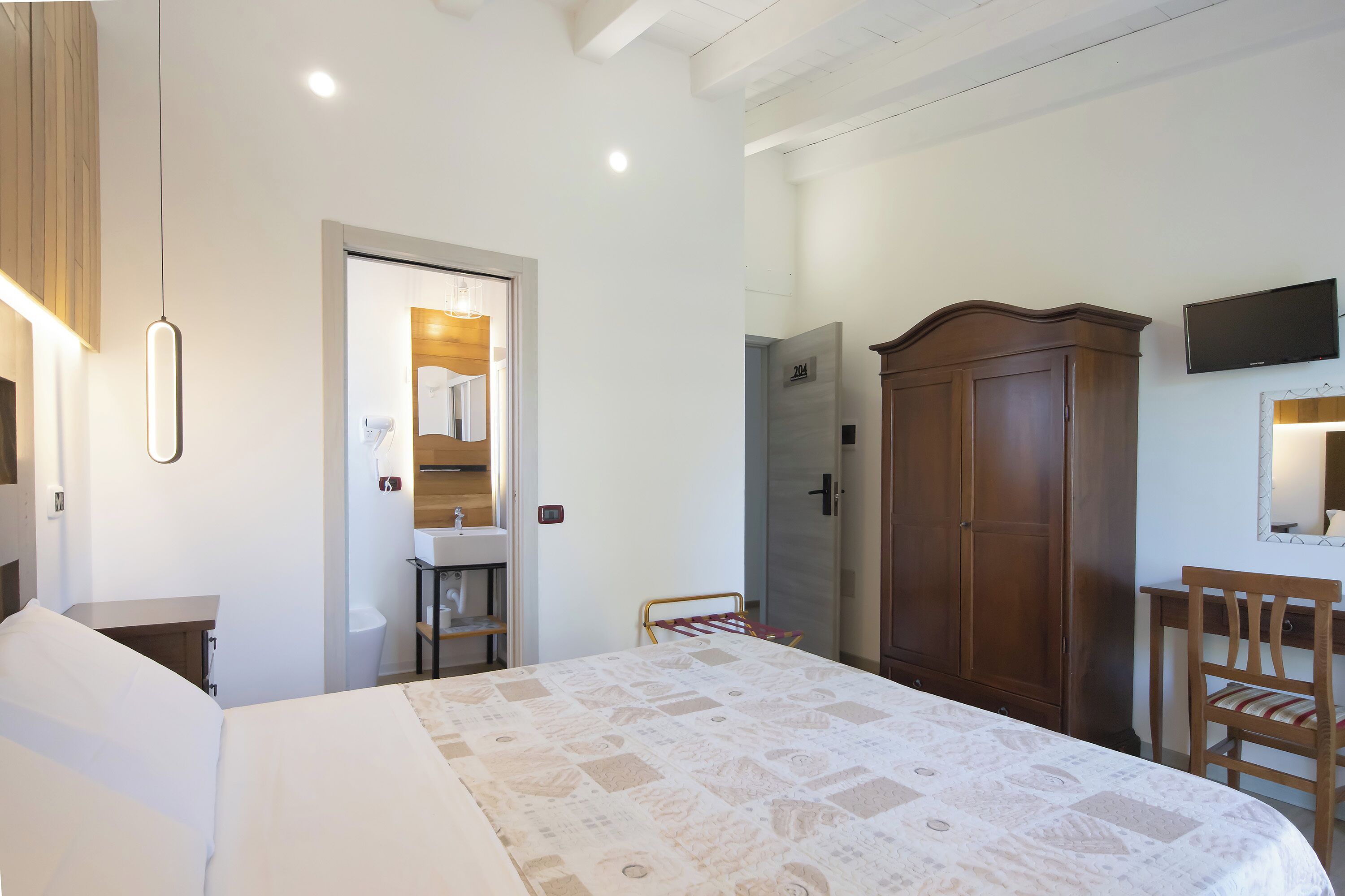 A bedroom with a bed, a wardrobe, a desk, and a television.