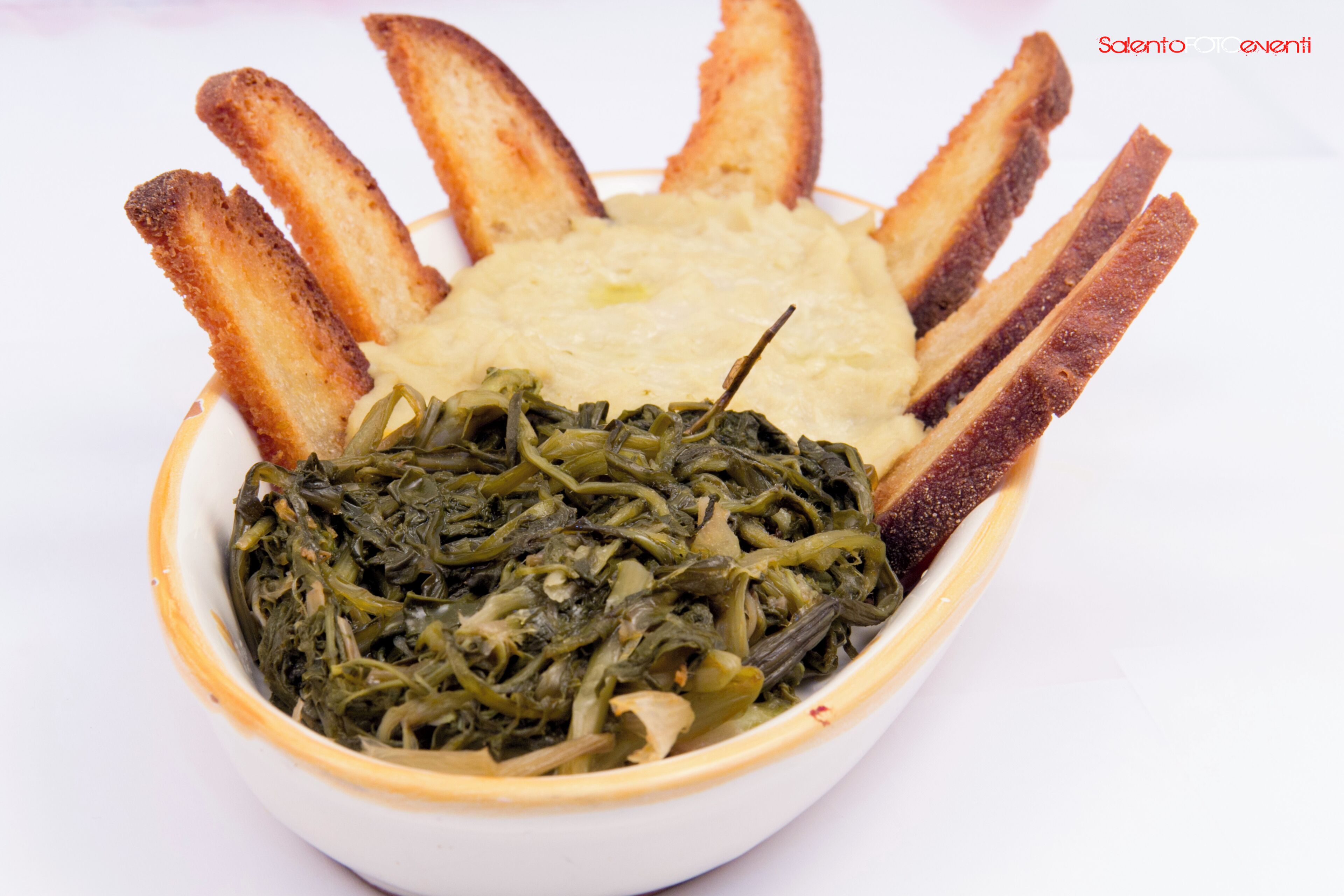 A bowl of food with breadsticks and greens.