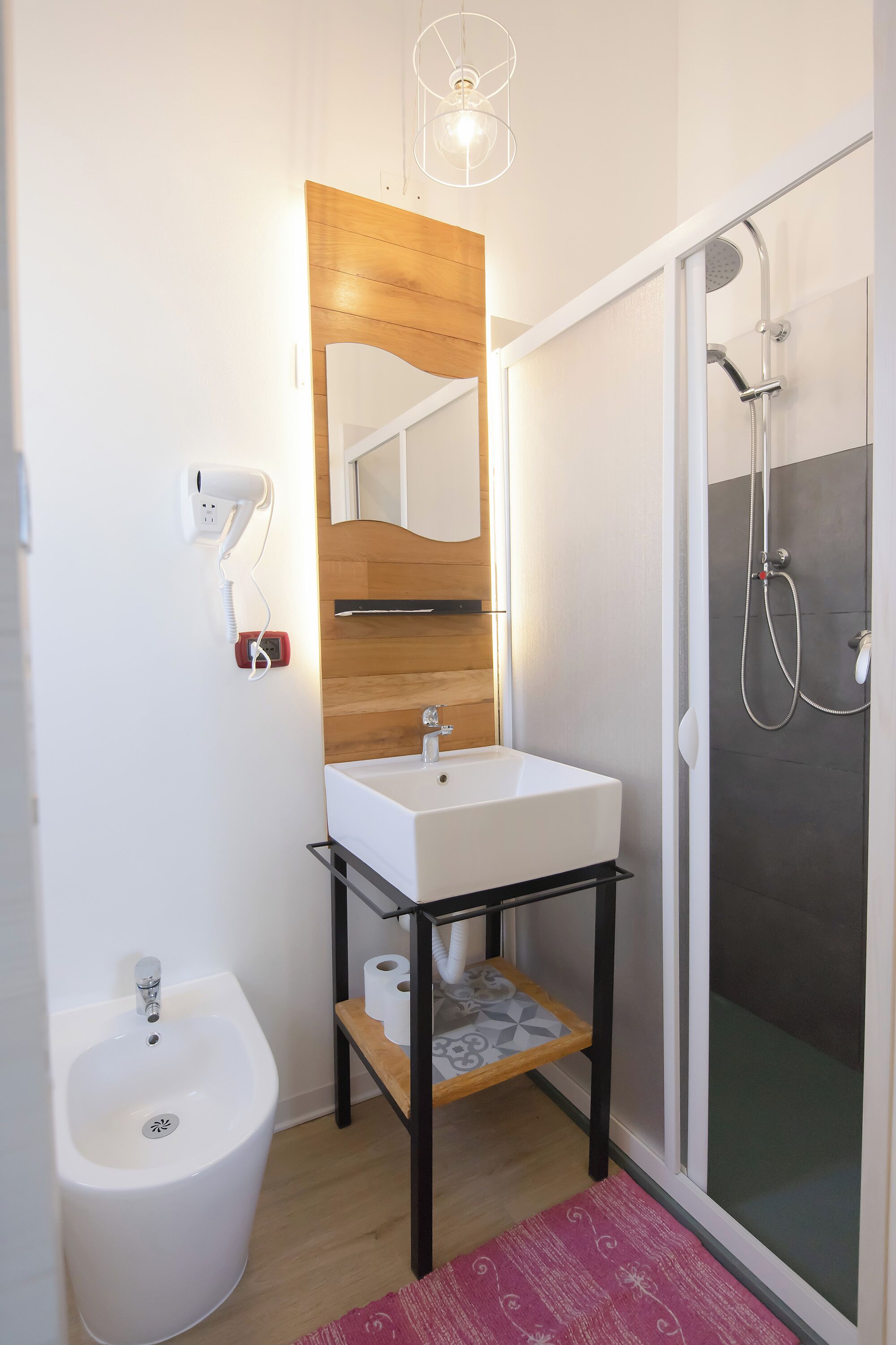 A modern bathroom with a white sink, wooden vanity, and a glass shower enclosure.