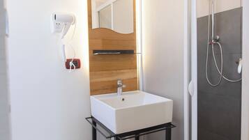 A modern bathroom with a white sink, wooden vanity, and a glass shower enclosure.