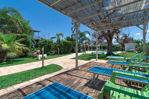 Un espace extérieur abrité comprenant une piscine, des chaises longues et un chemin menant à un bâtiment.