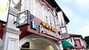 Un edificio con un letrero que dice 'le Peranakan Hotel' y otro letrero que anuncia 'Mai Thai Restaurant'.