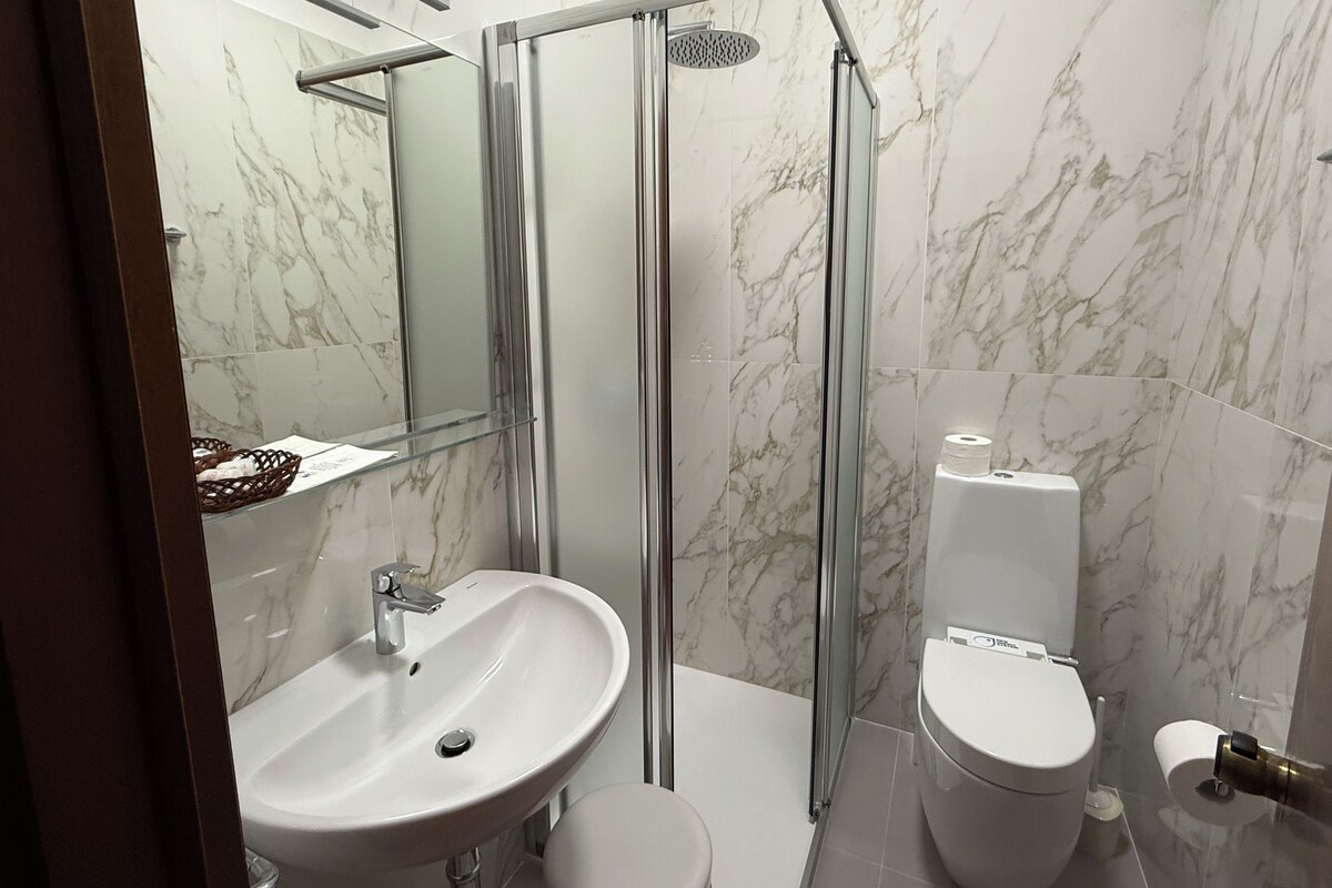 Une salle de bain moderne avec une douche à parois de verre, un lavabo blanc et des toilettes.
