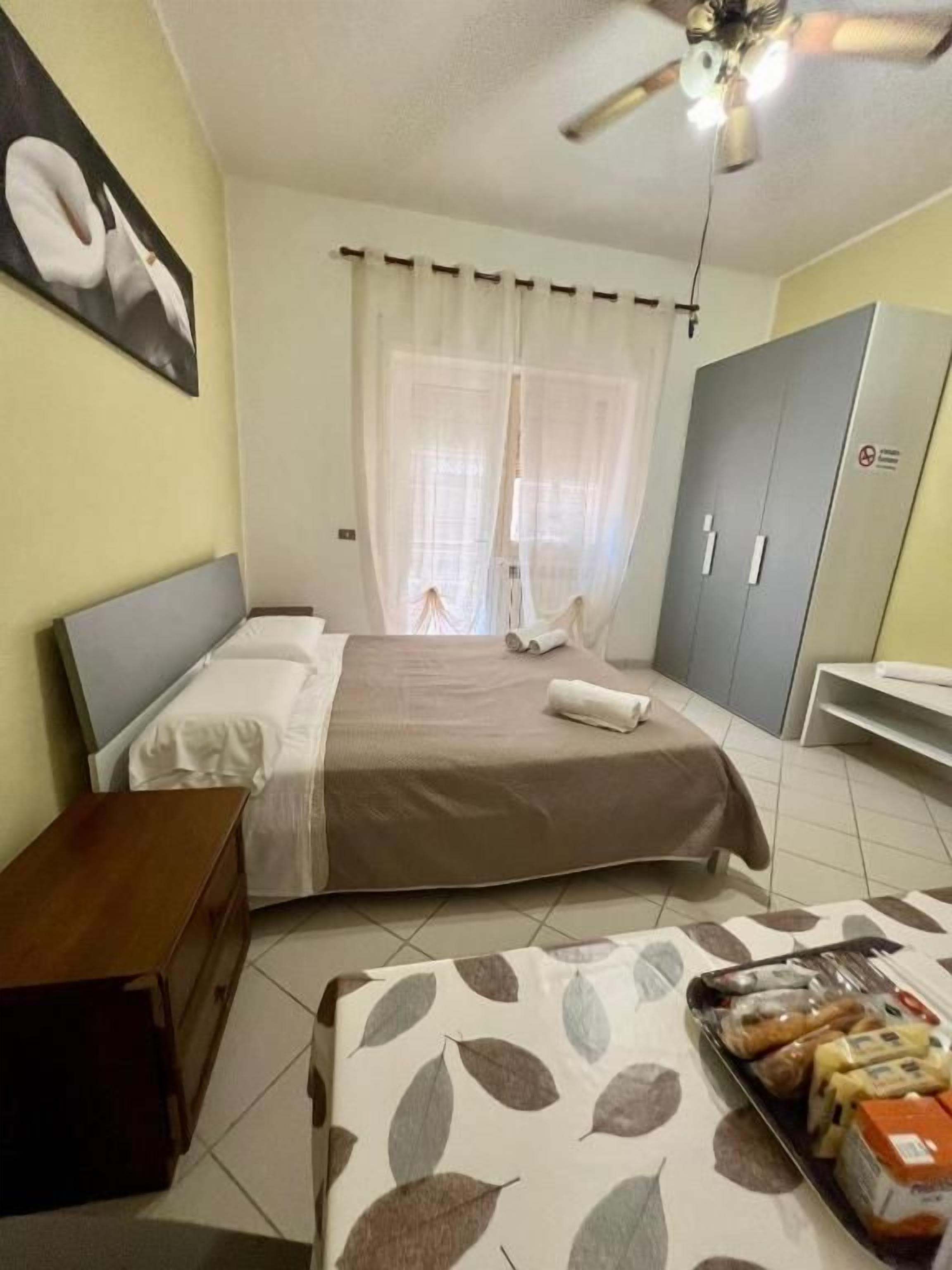 A bedroom with a bed, a bedside table, a wardrobe, and a tray of snacks.