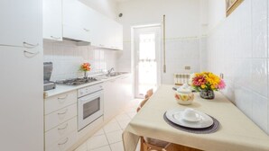 Una cocina moderna con armarios blancos, una estufa y una mesa de comedor para dos personas.