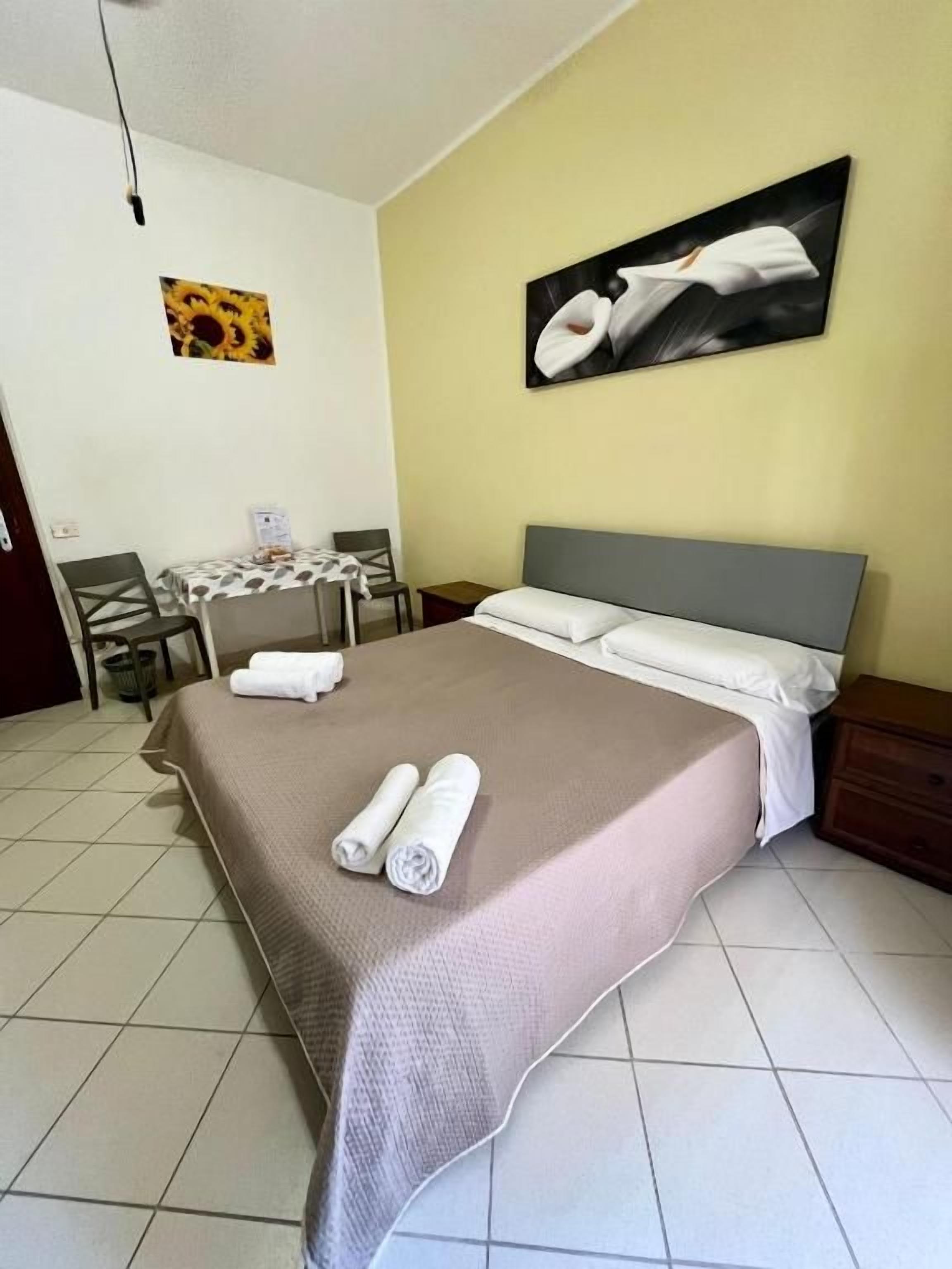 Une chambre d’hôtel avec un lit, une table et des chaises, et un tableau accroché au mur.