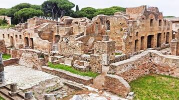Ancient ruins with stone columns and arches, surrounded by greenery.