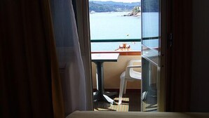 Ein Zimmer mit Bett, Tisch und Stuhl, mit Blick auf ein Gewässer und einen Steg.