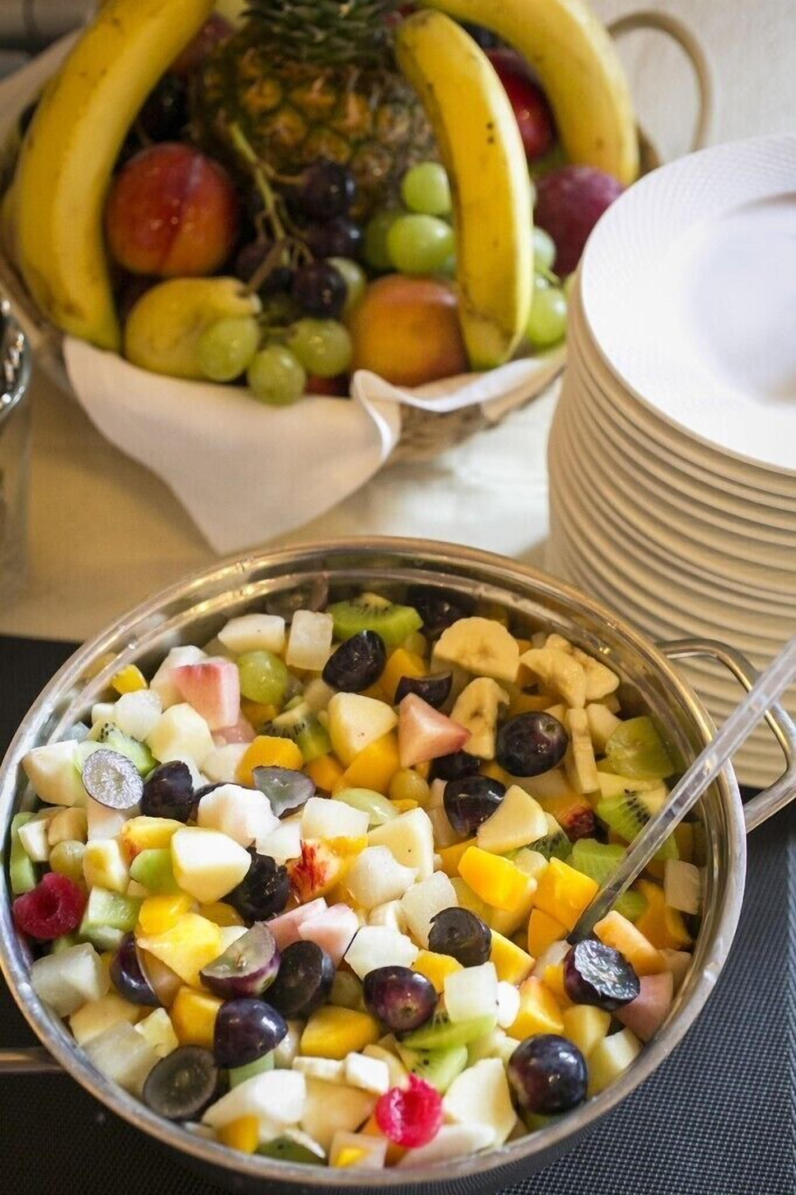 Uma saladeira com salada de frutas variadas e uma tigela à parte com bananas e abacaxis.